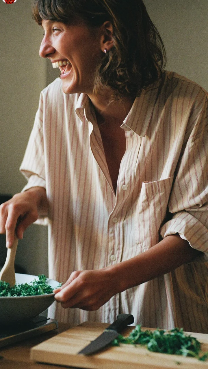 A dating profile photo: someone laughing while cooking in a sunlit kitchen